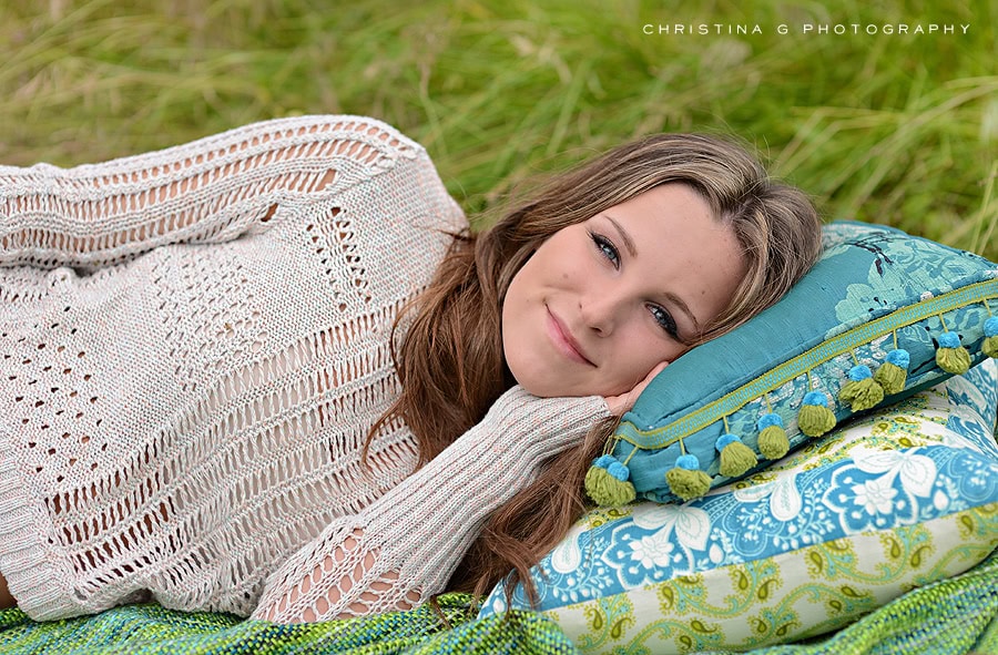 PRETTY TEEN GIRL LAYING ON PILLOWS IN FIELD