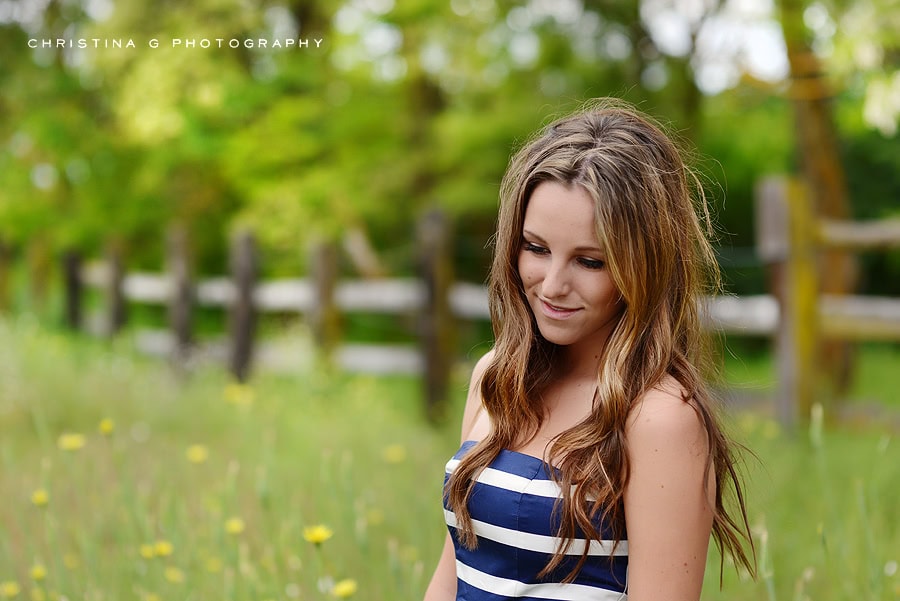 PRETTY TEEN GIRL IN FIELD OF FLOWERS WITH BLUE AND WHITE DRESS LOOKING DOWN