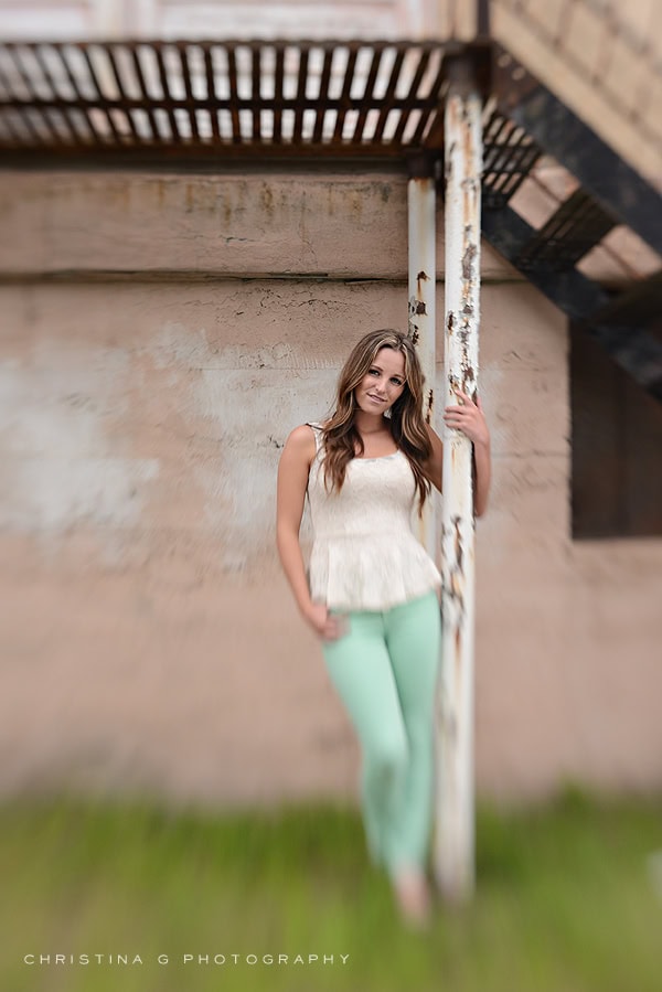 PRETTY TEEN GIRL WITH CREAM TANK TOP AND SOFT SMILE HOLDING ONTO A POLE