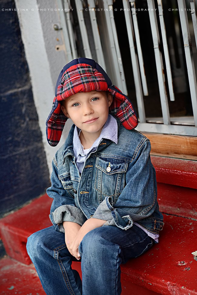 YOUNG BOY WITH PLAID WINTER HAT SITTING ON RED STEPS IN MIDTOWN COEUR D'ALENE