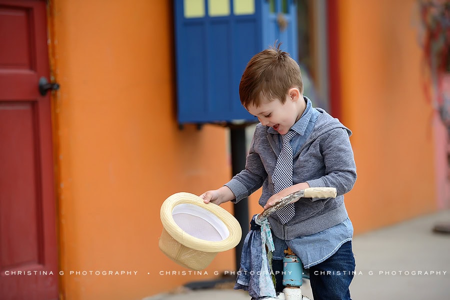 LITTLE BOY WITH A TIE IN FRONT OF COLORFUL WALL ON TRICYCLE