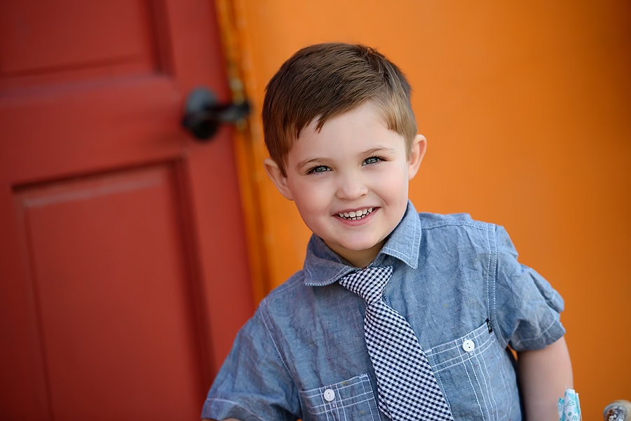 LITTLE BOY WITH A TIE IN FRONT OF COLORFUL WALL